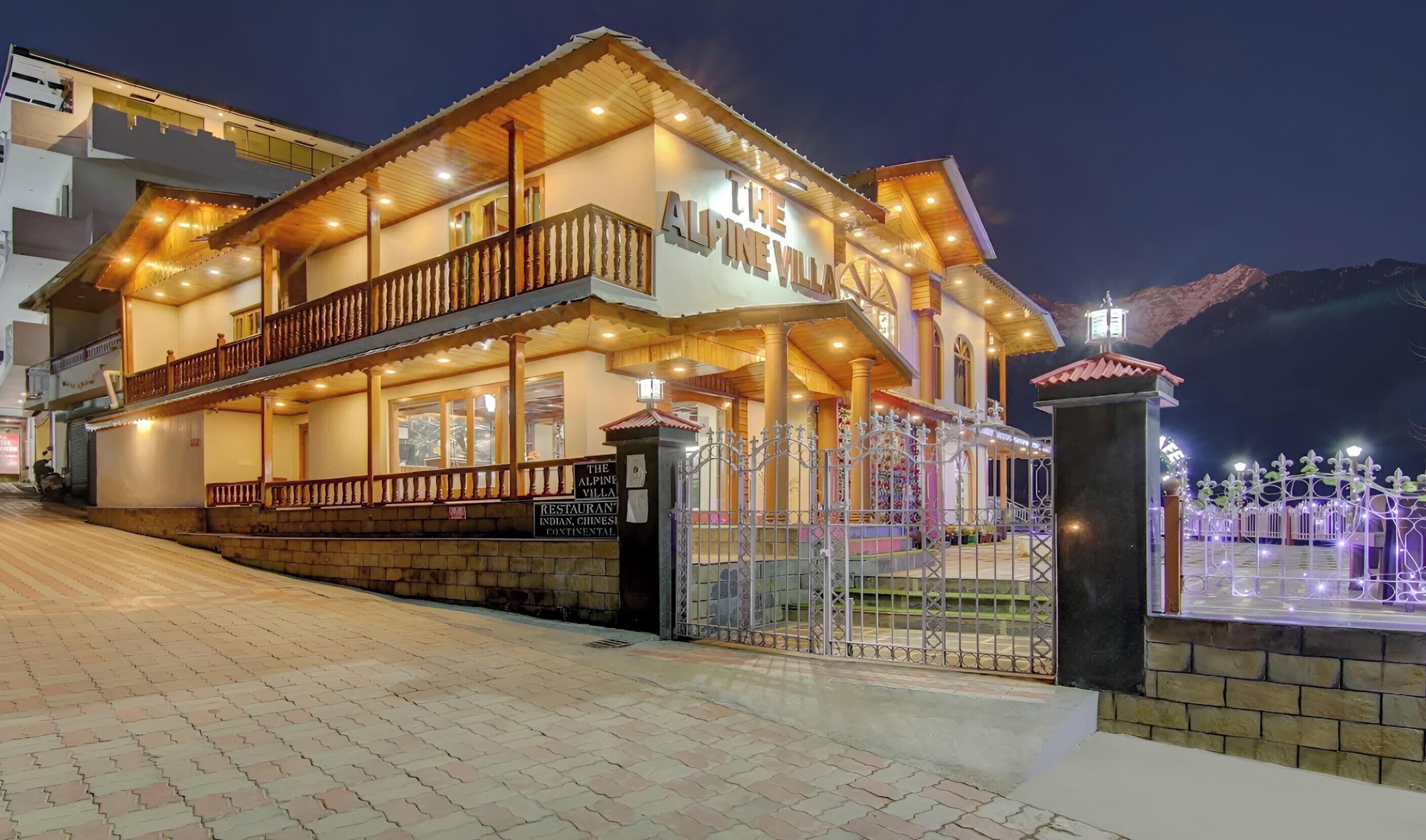 A two-story hotel with a balcony, a sign indicating it is a restaurant, and a gate with decorative lights.