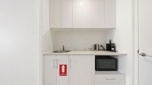 A small kitchenette with a sink, a microwave, a kettle, and a fire extinguisher. - MetaWise 1Bed Next Darling Harbour 115 (Sydney)