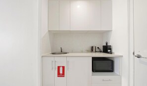 A small kitchenette with a sink, a microwave, a kettle, and a fire extinguisher. - MetaWise 1Bed Next Darling Harbour 115 (Sydney)