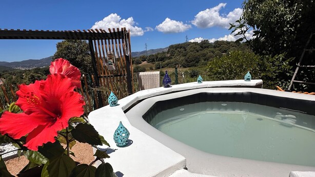 A hot tub with a clear view of the surrounding landscape, a pergola, and a potted red flower. - 🌿 Charming house with jacuzzi & open view - Haven of peace 🌞 (Bastelicaccia)