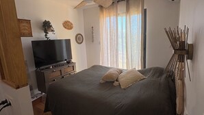 A bedroom with a bed, a ceiling fan, a TV, and a bedside table. - 🌿 Charming house with jacuzzi & open view - Haven of peace 🌞 (Bastelicaccia)