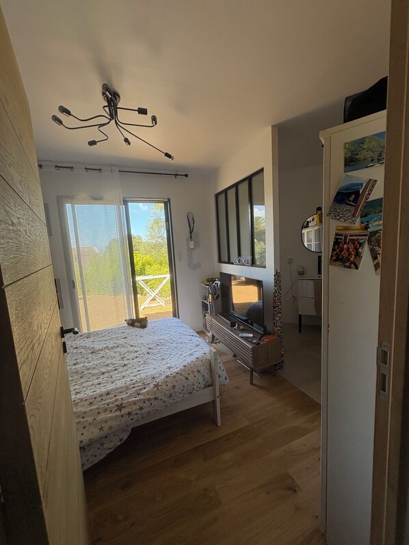 A bedroom with a bed, a TV, and a balcony.