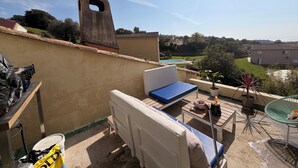 A rooftop terrace with a view of a swimming pool, a stone chimney, and a table with outdoor furniture. - 🌿 Charming house with jacuzzi & open view - Haven of peace 🌞 (Bastelicaccia)