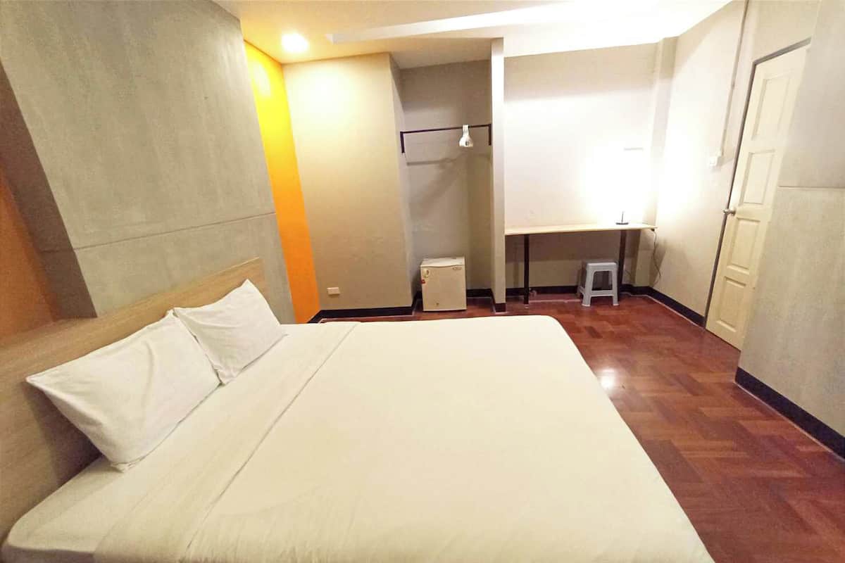 Een hotelkamer met een bed, een bureau, een stoel en een klein krukje.