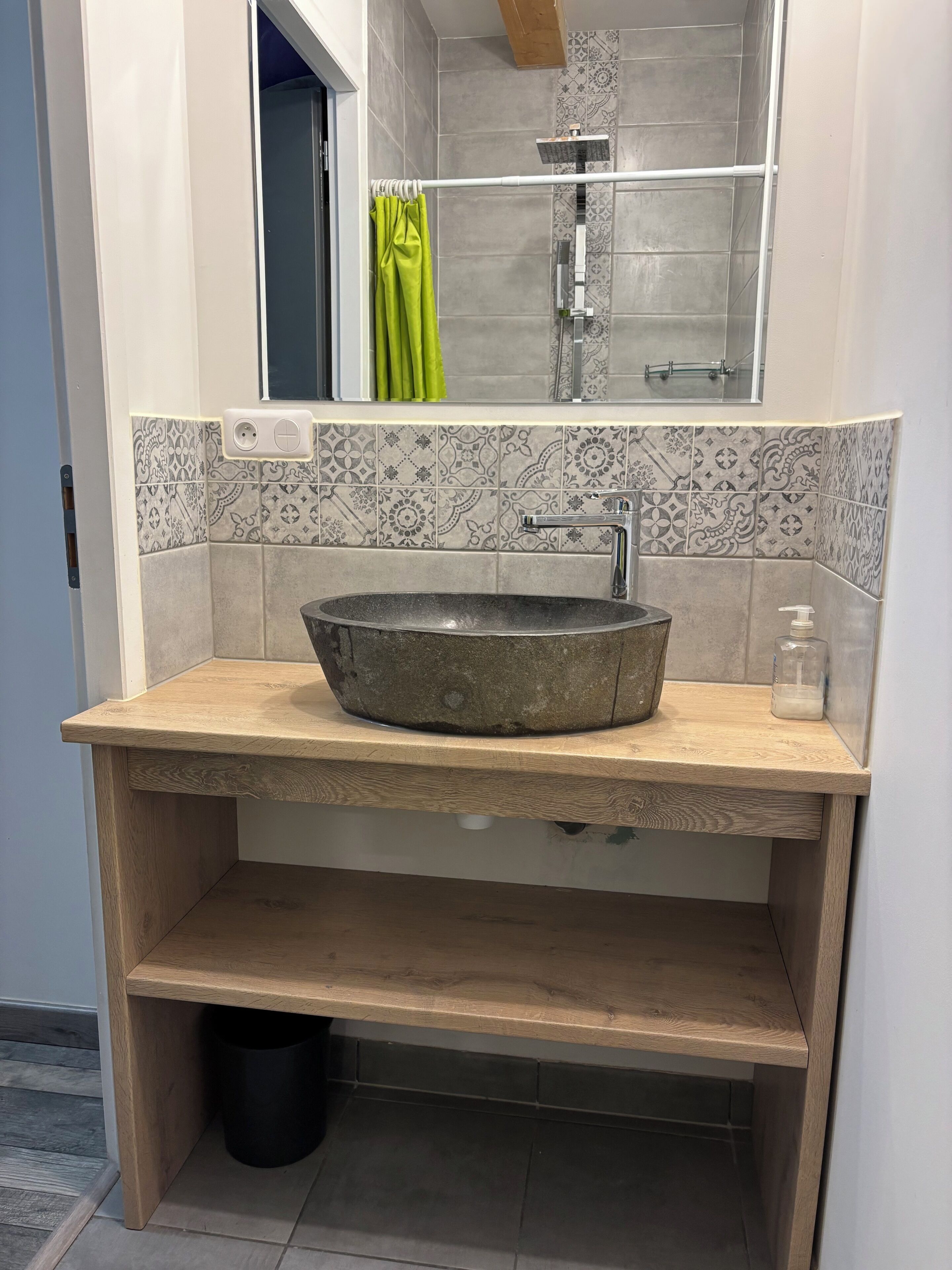 Een badkamer met een ronde wasbak, een spiegel en betegelde vloeren.