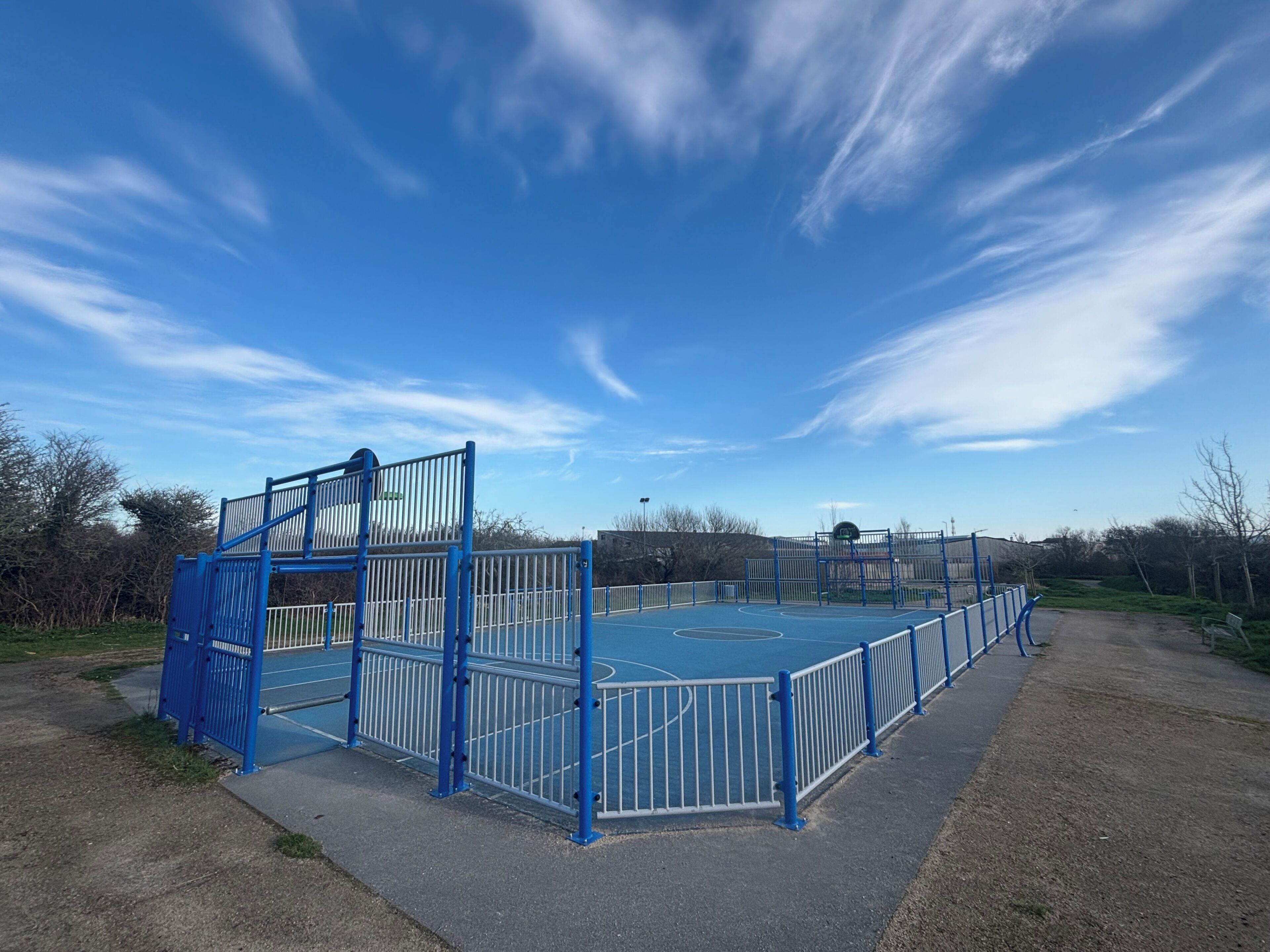 Un terrain de basket avec des barrières bleues et une clôture en métal.