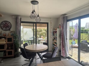 Een eetruimte met een ronde tafel, stoelen, een klok en een boekenkast.