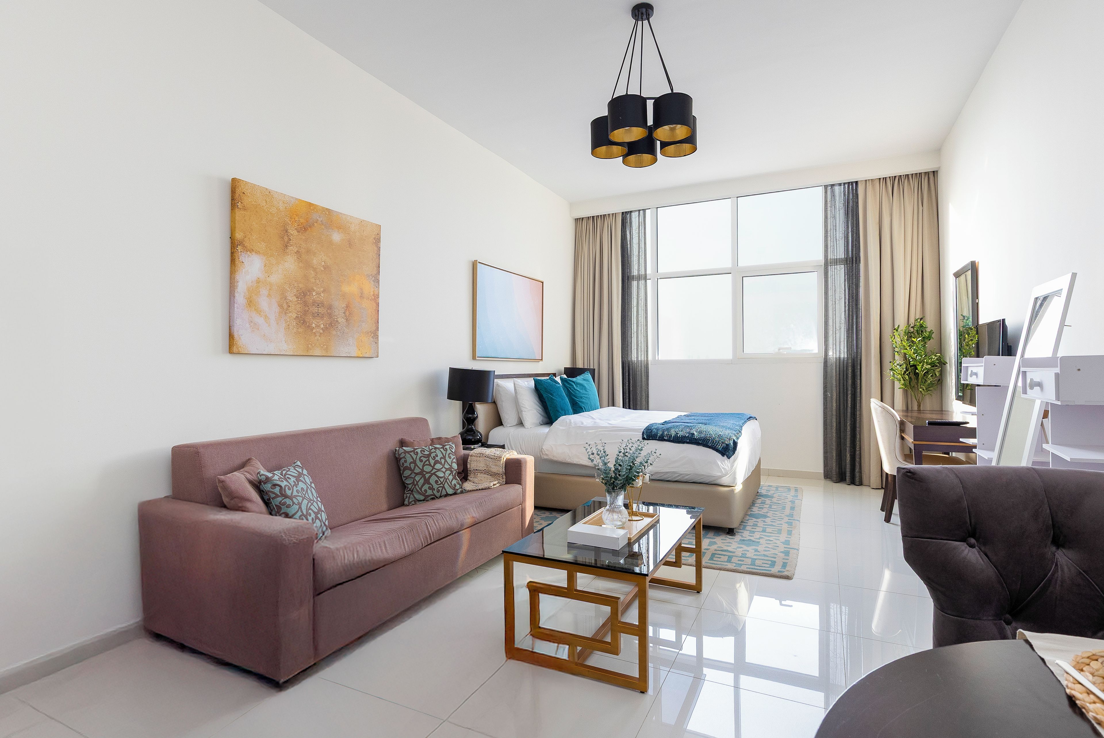A modern living room with a sofa, a bed, a coffee table, and a desk.