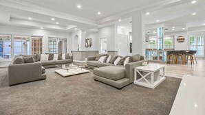 Un vaste espace de vie comprenant un grand canapé, une table basse et un coin repas avec des chaises.