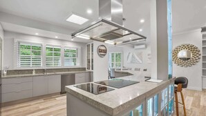 Une cuisine moderne dotée d’un îlot central, d’appareils électroménagers intégrés et offrant une vue sur l’espace de vie.