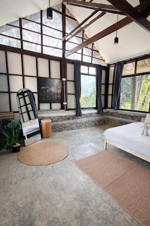 A room with a bed, a large window, a stone wall, and a hanging light fixture. - Drifter's Anchor (Ko Chang)