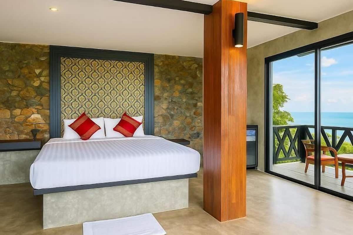 A bedroom with a bed, a stone wall, a wooden column, and a balcony with a view.