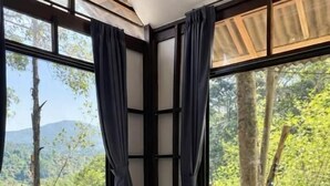 A room with a stone wall, large windows with curtains, and a bed. - Drifter's Anchor (Ko Chang)