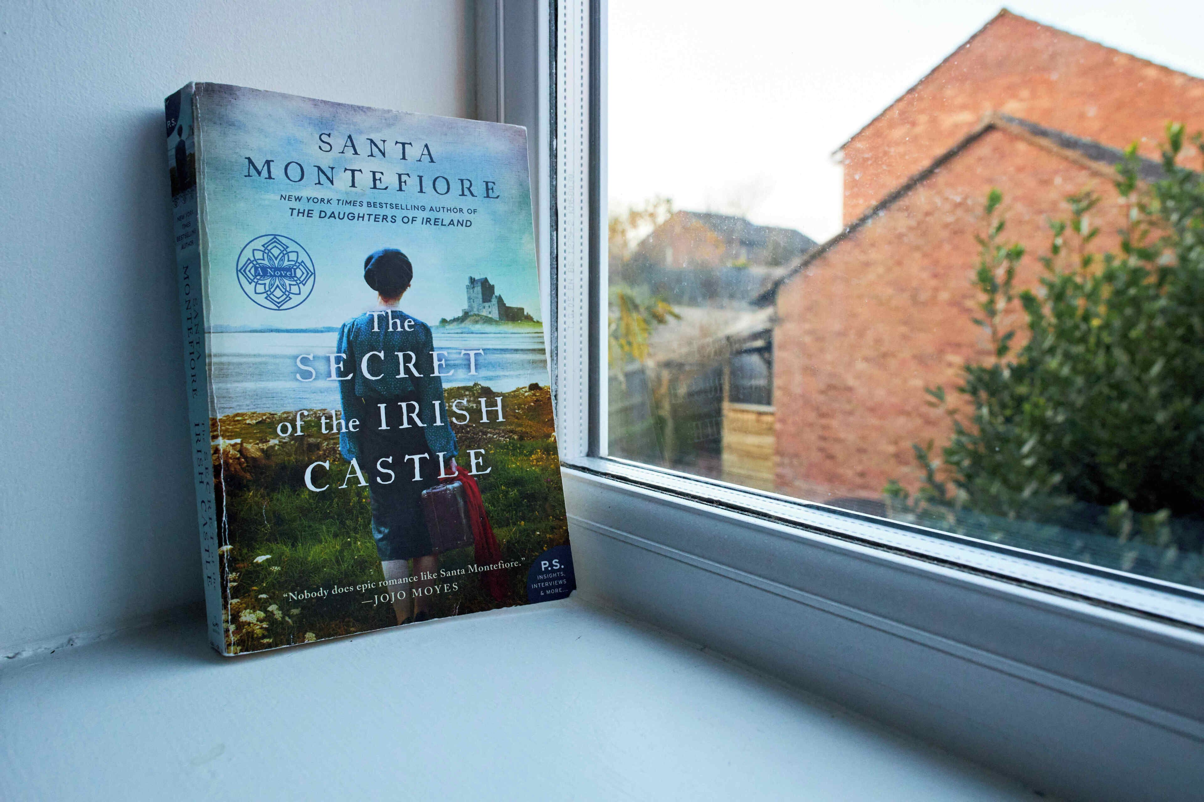 A book titled 'The Secret of the Irish Castle' by Santa Montefiore on a windowsill.