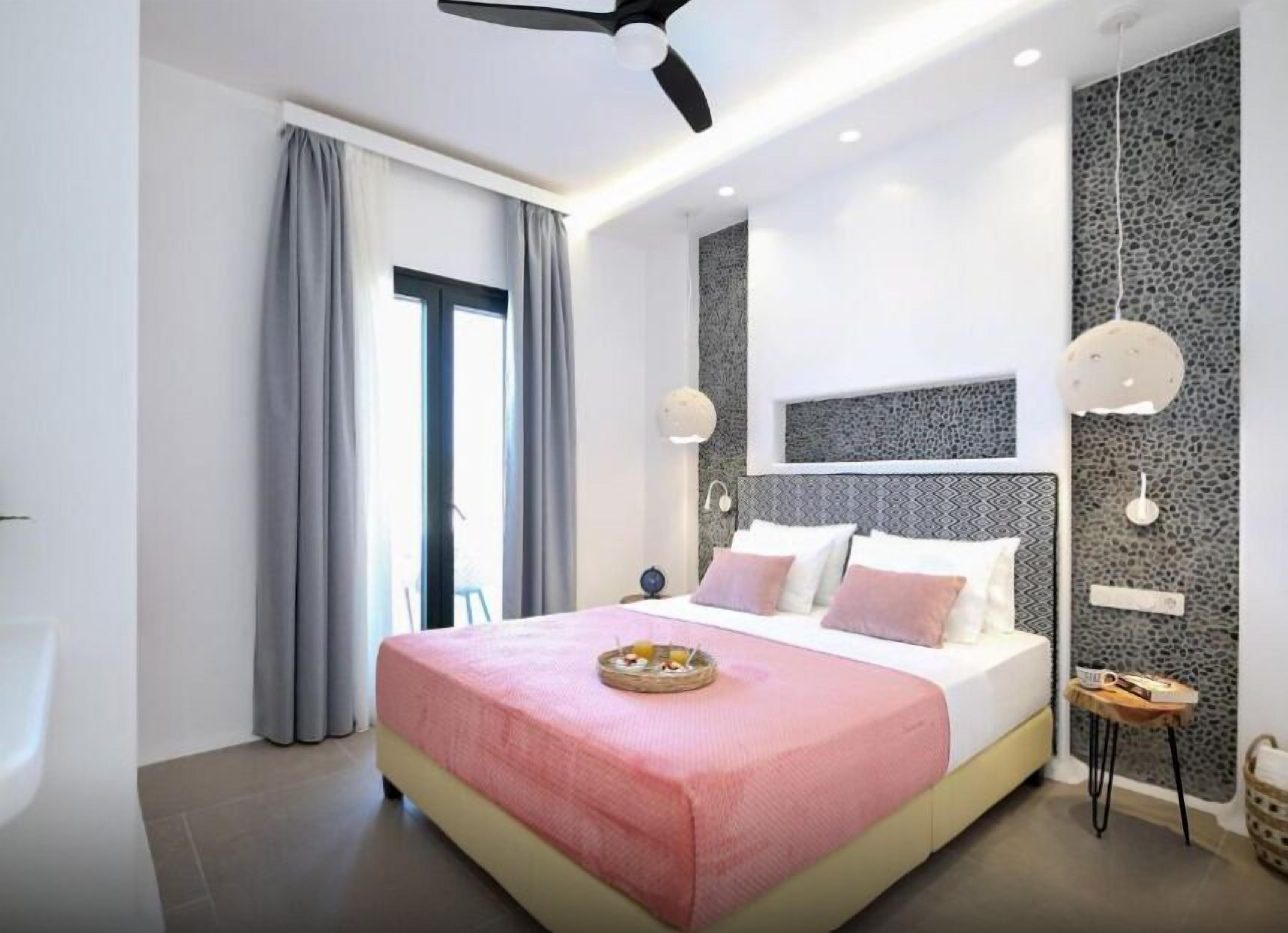 A modern bedroom with a bed, curtains, a ceiling fan, and a wall with a textured pattern.