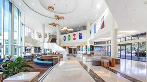 A spacious lobby with a central staircase, seating areas, and a reception desk. - Skyline Stay with Balcony (Gold Coast)