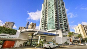 A high-rise hotel with a modern design, featuring a prominent entrance and a visible parking area. - Skyline Stay with Balcony (Gold Coast)