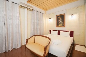 A bedroom with a bed, a chair, a painting, and an air conditioning unit. - Mitr Inn Yaowarat (Bangkok)
