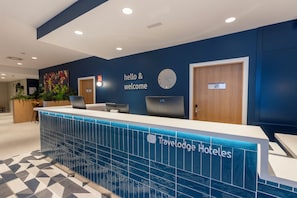 A reception desk with a 'hello & welcome' sign, a clock, and a 'Travelodge Hotels' logo. - Travelodge Bilbao Sestao (Sestao)