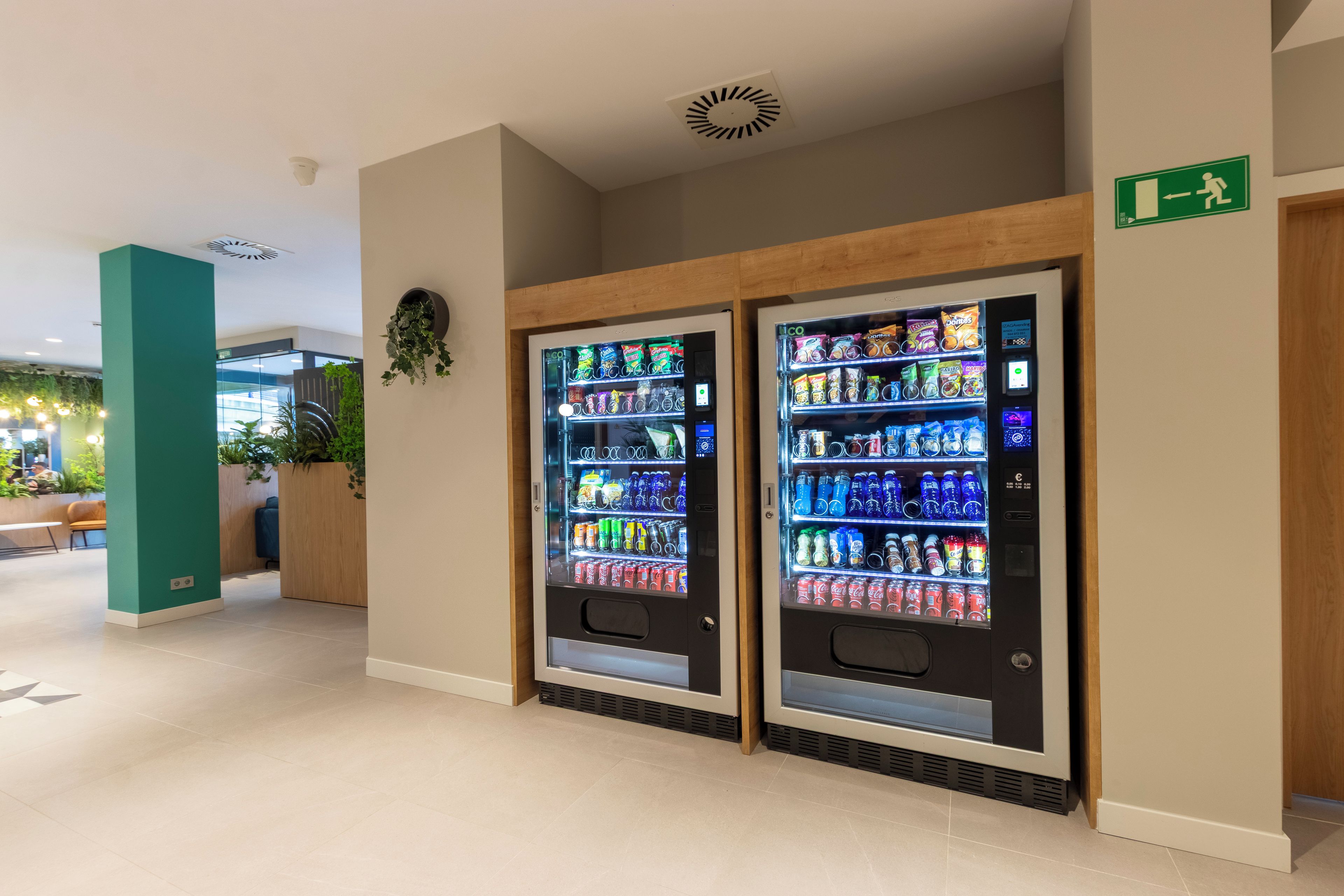 Dos máquinas expendedoras de bebidas en un ambiente interior moderno.