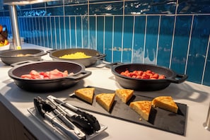 Een buffet met diverse gerechten, waaronder vleeswaren en groenten, en een keuze uit geroosterd brood.