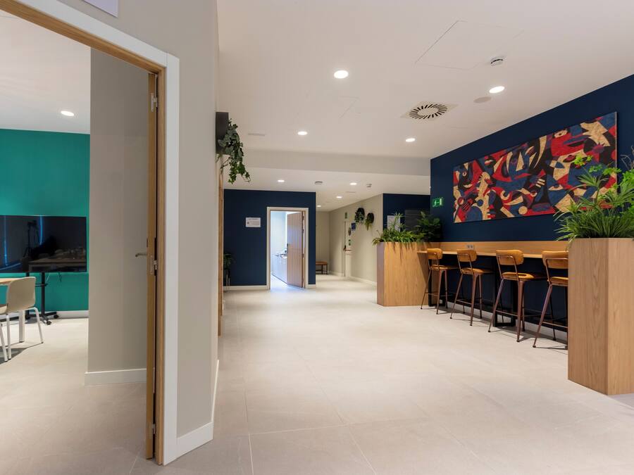 Un moderno vestíbulo de hotel con una pared de acento color turquesa, una recepción y una zona de bar.