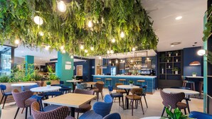 Een restaurant met hangplanten, ronde tafels en stoelen.