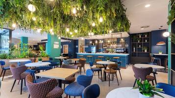 Un restaurante con plantas colgantes, mesas redondas y sillas.