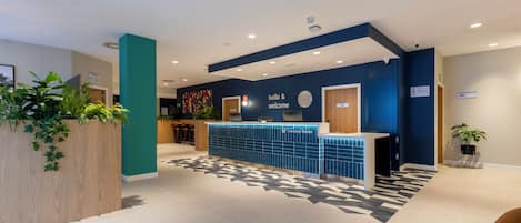 A reception area with a blue reception desk, a clock, and a 'hello & welcome' sign.