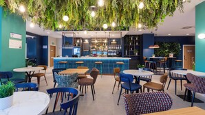 Een restaurant met hangplanten, een bar en verschillende zithoeken.