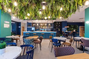 Un restaurant agrémenté de plantes suspendues, doté d’un bar et offrant différents types de sièges.