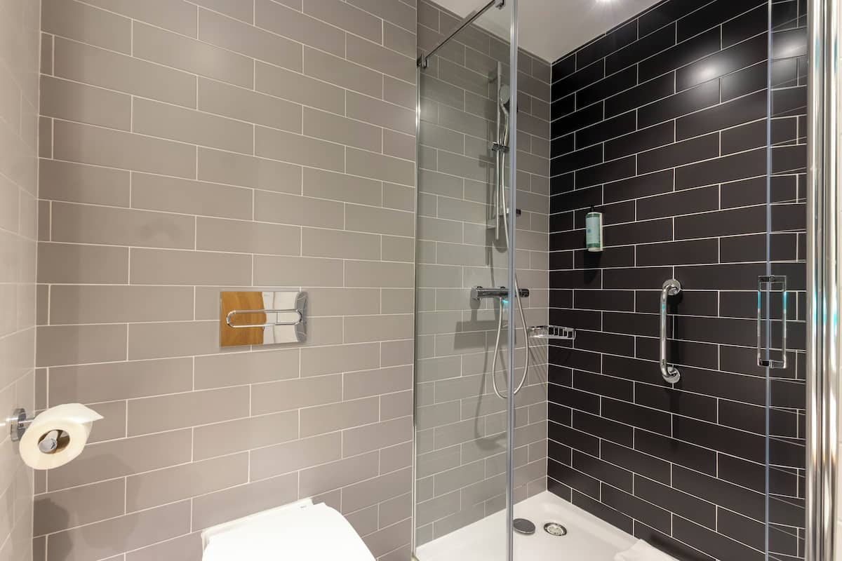 Een moderne badkamer met een glazen douchecabine, een toilet en een handdoekhouder.