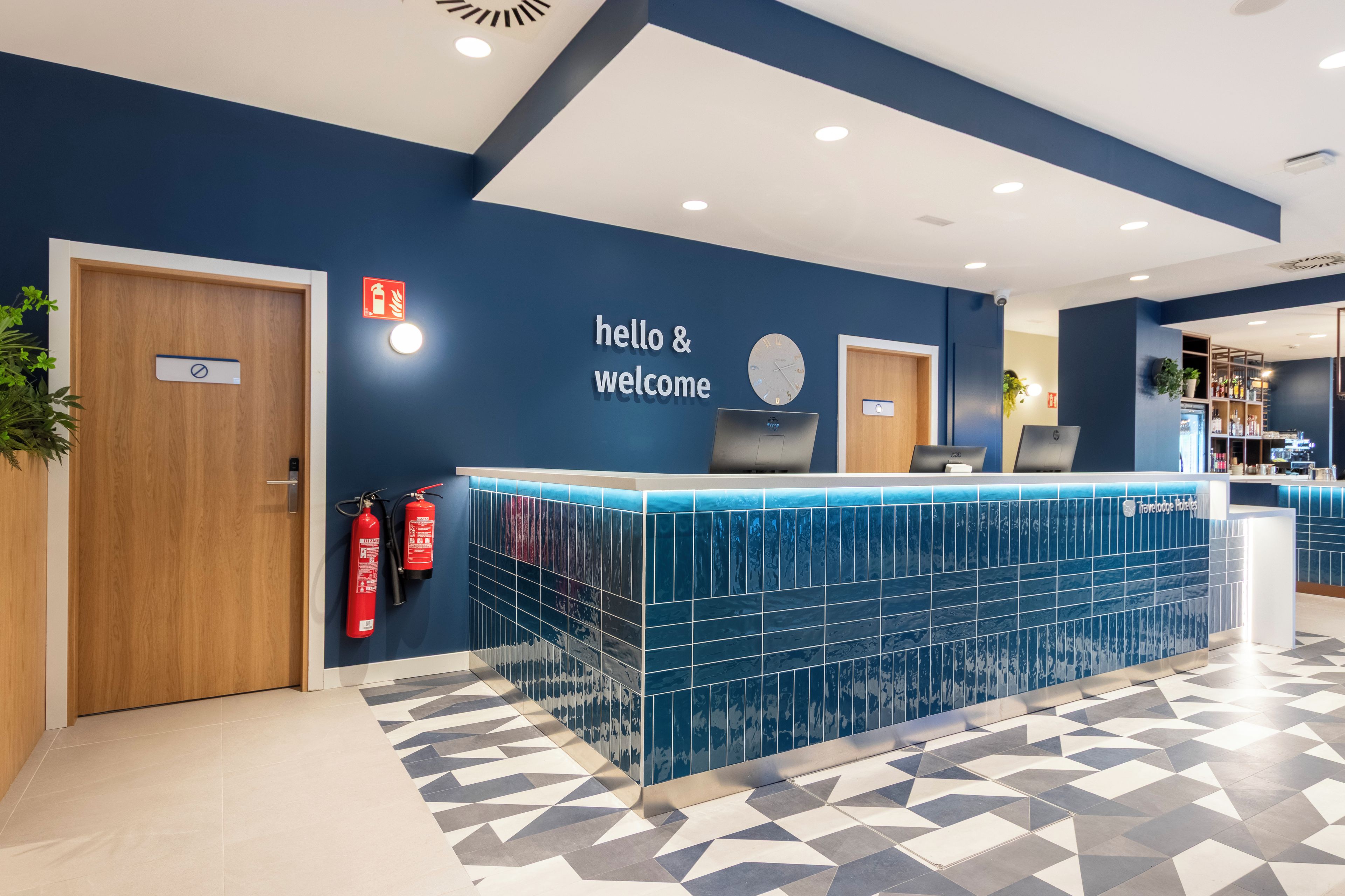 Una recepción con un cartel que dice 'hello & welcome', un reloj y un extintor.