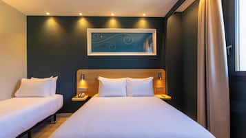 Een hotelkamer met twee bedden, een hoofdeinde, bedlampen, een kunstwerk aan de muur en een raam met gordijnen.