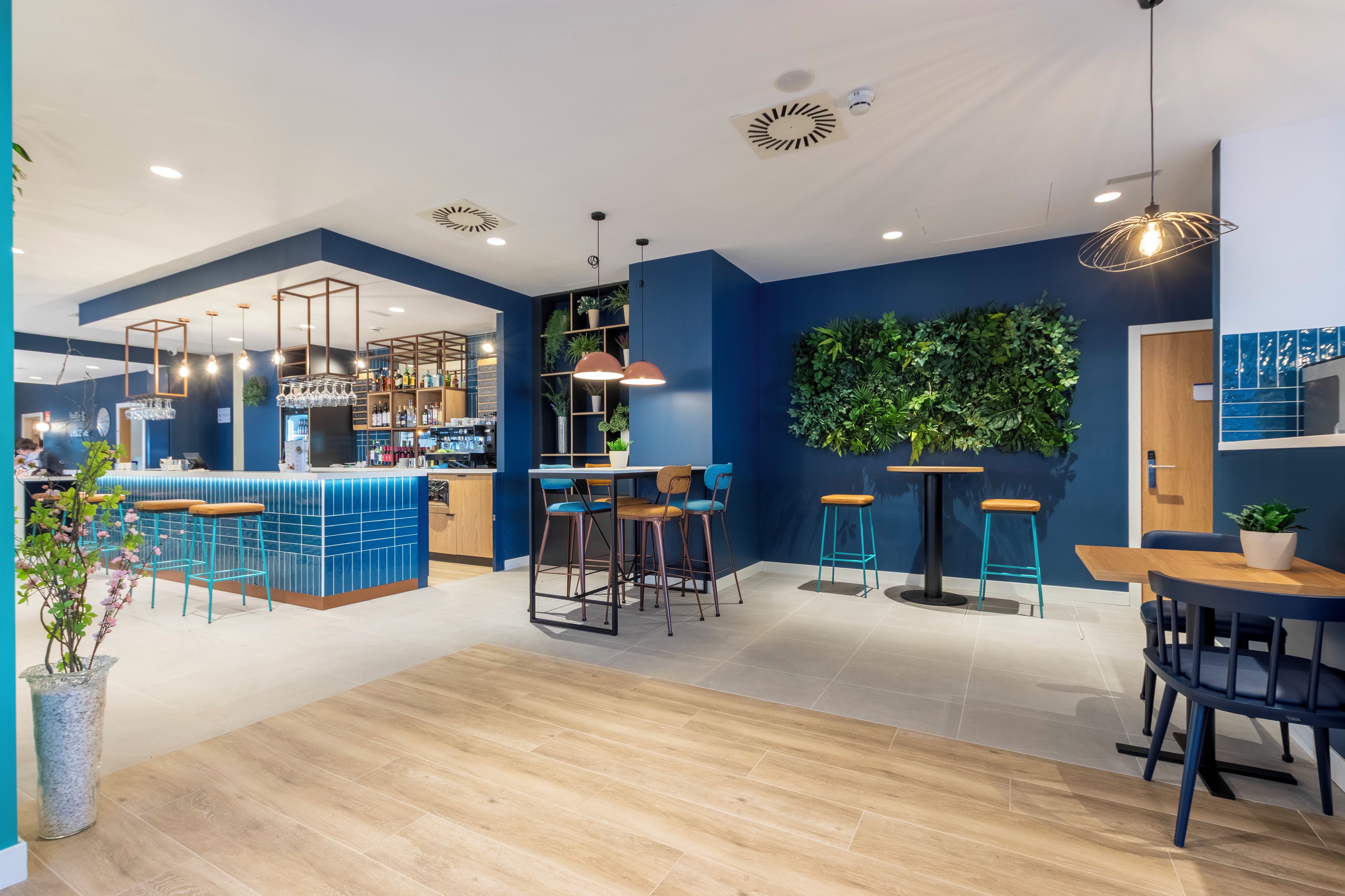 Un moderno espacio de bar con barra, taburetes y luces colgantes.