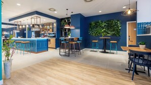 Een moderne bar met een toonbank, krukken en hangende lampen.
