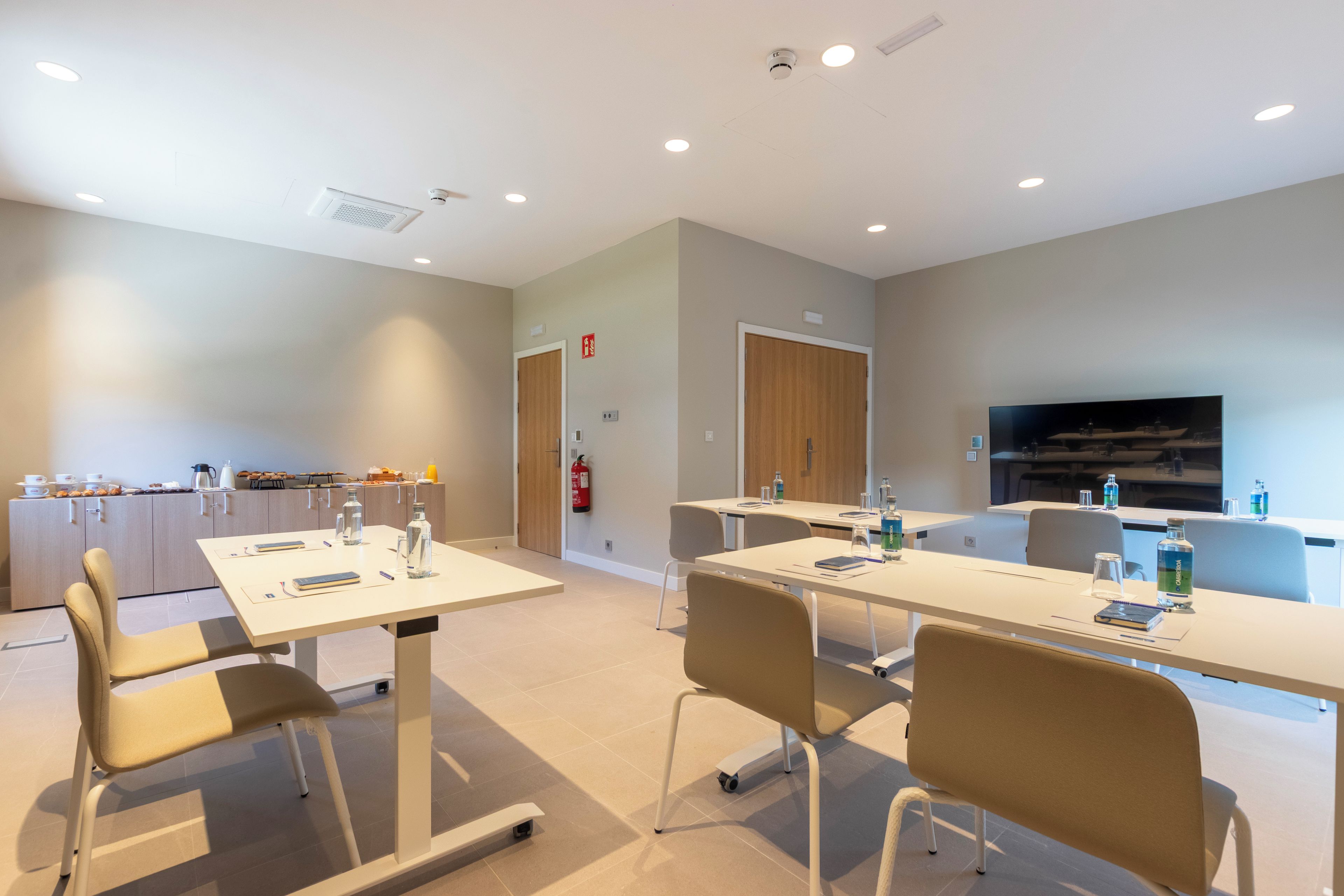 Une chambre d’hôtel moderne dotée d’un coin repas, d’un téléviseur à écran plat et d’une kitchenette.