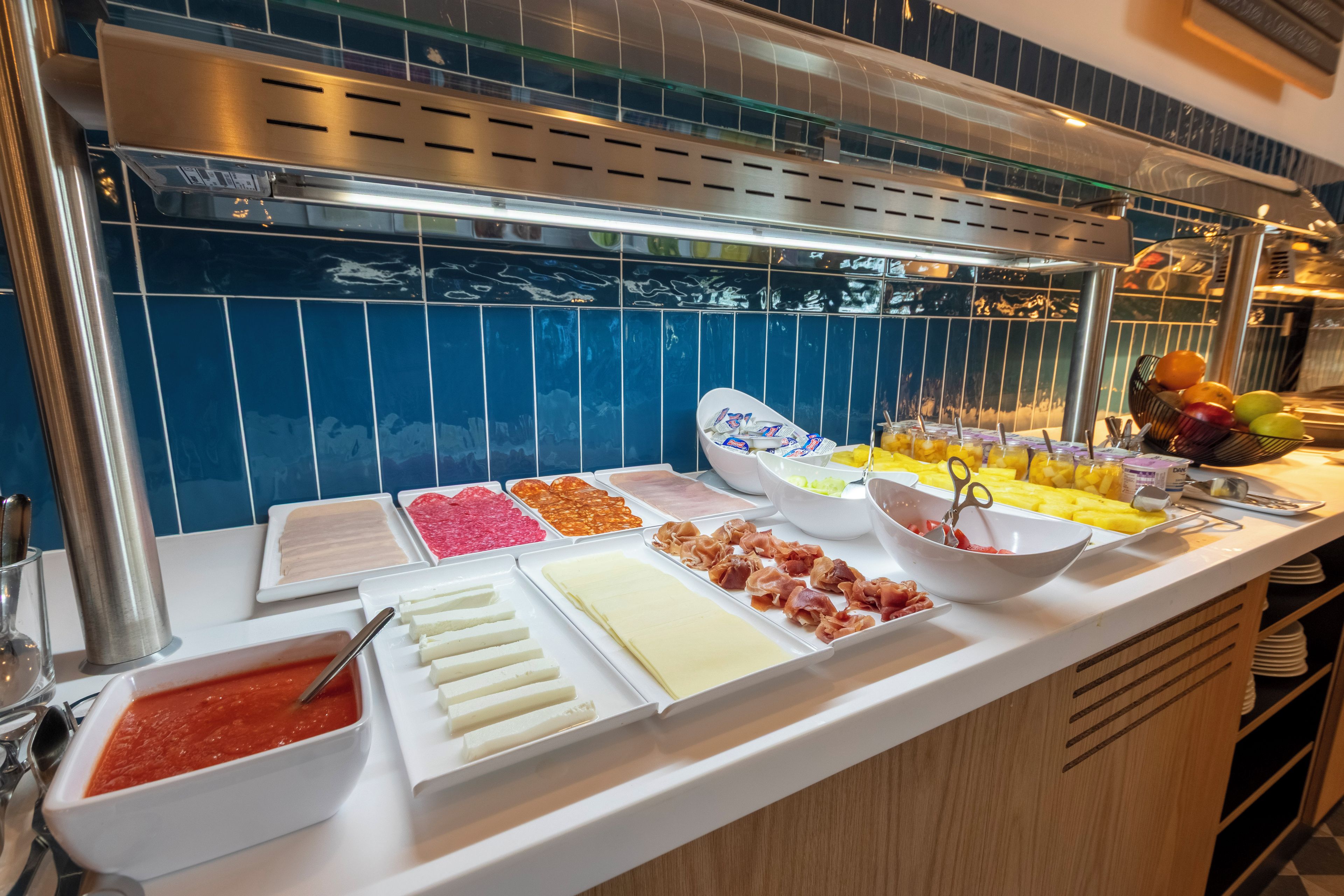 Een buffet met diverse gerechten, zoals vleeswaren, kazen en fruit.