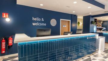 A reception desk with a 'hello & welcome' sign, a clock, and a fire extinguisher.