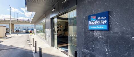 A modern hotel entrance with a sign for 'Hoteles Travelodge Bilbao Sestao.'