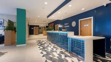 A reception area with a blue tiled counter, a clock, and a sign that reads 'hello & welcome'.