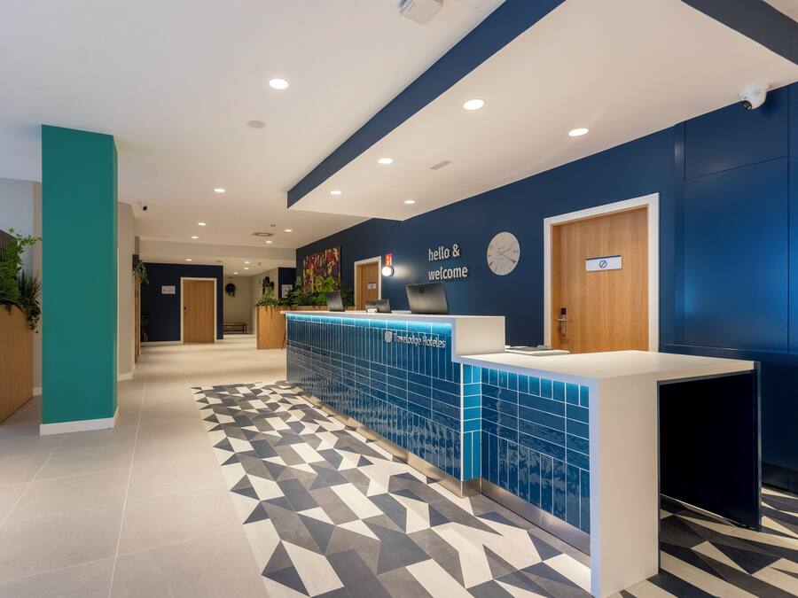 A reception area with a blue tiled counter, a clock, and a sign that reads 'hello & welcome'.