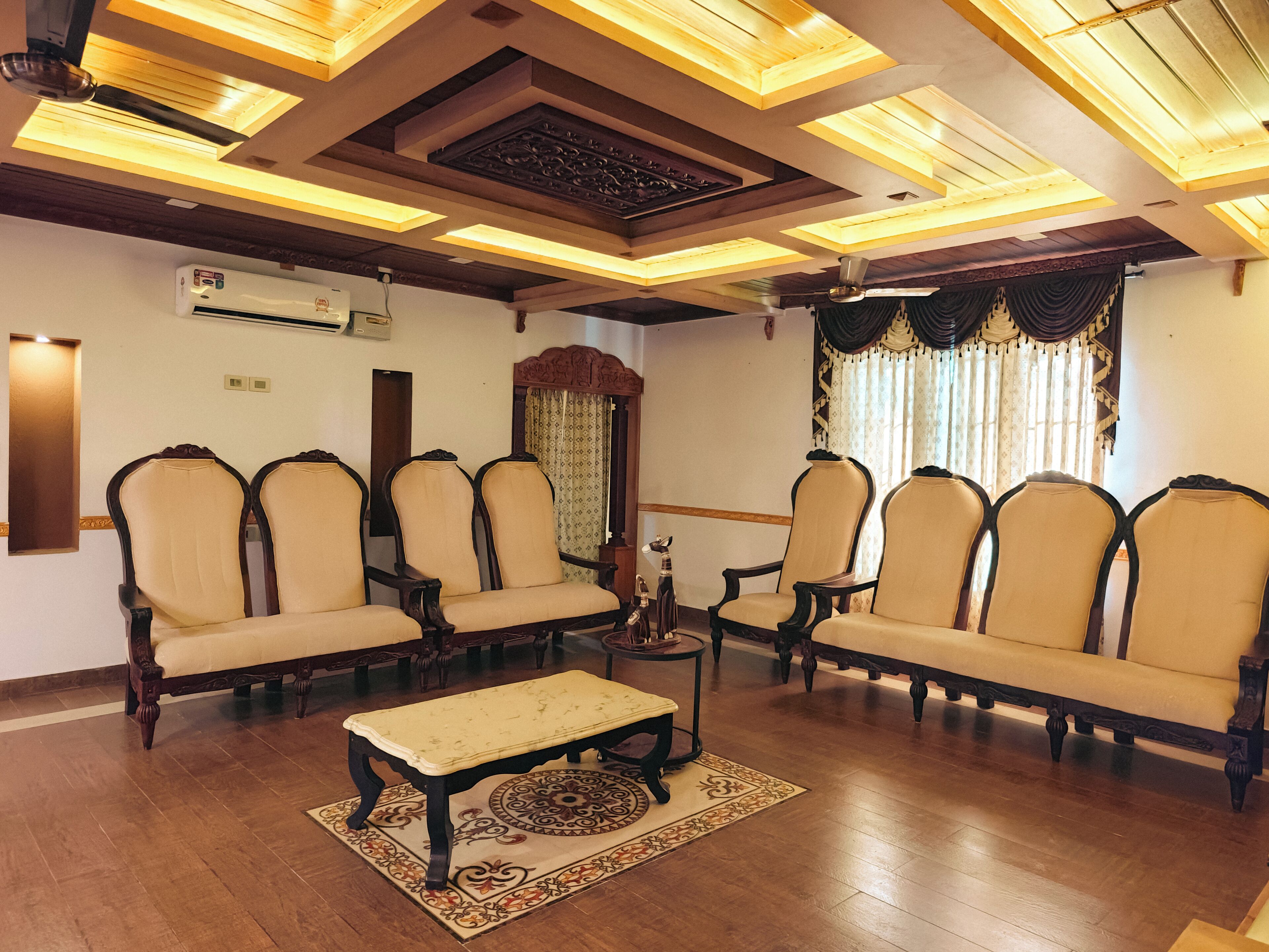 A room with a wooden floor, a sofa set, a coffee table, and a ceiling with skylights.