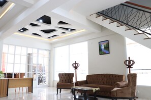 Una habitación amplia con techo alto, una escalera, un ventanal grande y un sofá.