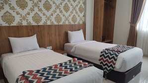 A hotel room with two beds, a wooden headboard, a wardrobe, and a patterned wall. - Edu Hotel Y-skanam (Surabaya)