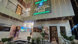 A hotel atrium with a sign reading 'ANTILLA INN,' multiple balconies, indoor plants, and artwork on the walls. - Antilia Inn (Badami)