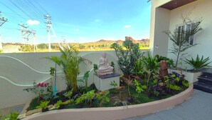 A landscaped garden with a statue, a building with a window, and a clear sky. - Antilia Inn (Badami)