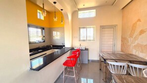A kitchen with a central island, a dining area with a table and chairs, and a window with blinds.