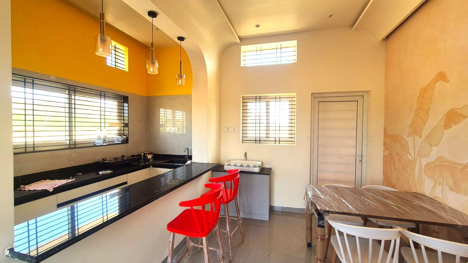 A kitchen with a black countertop, red bar stools, and a dining table with white chairs.