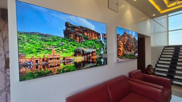 Un interior moderno con una gran obra de arte en la pared que representa un complejo de templos y una escalera.